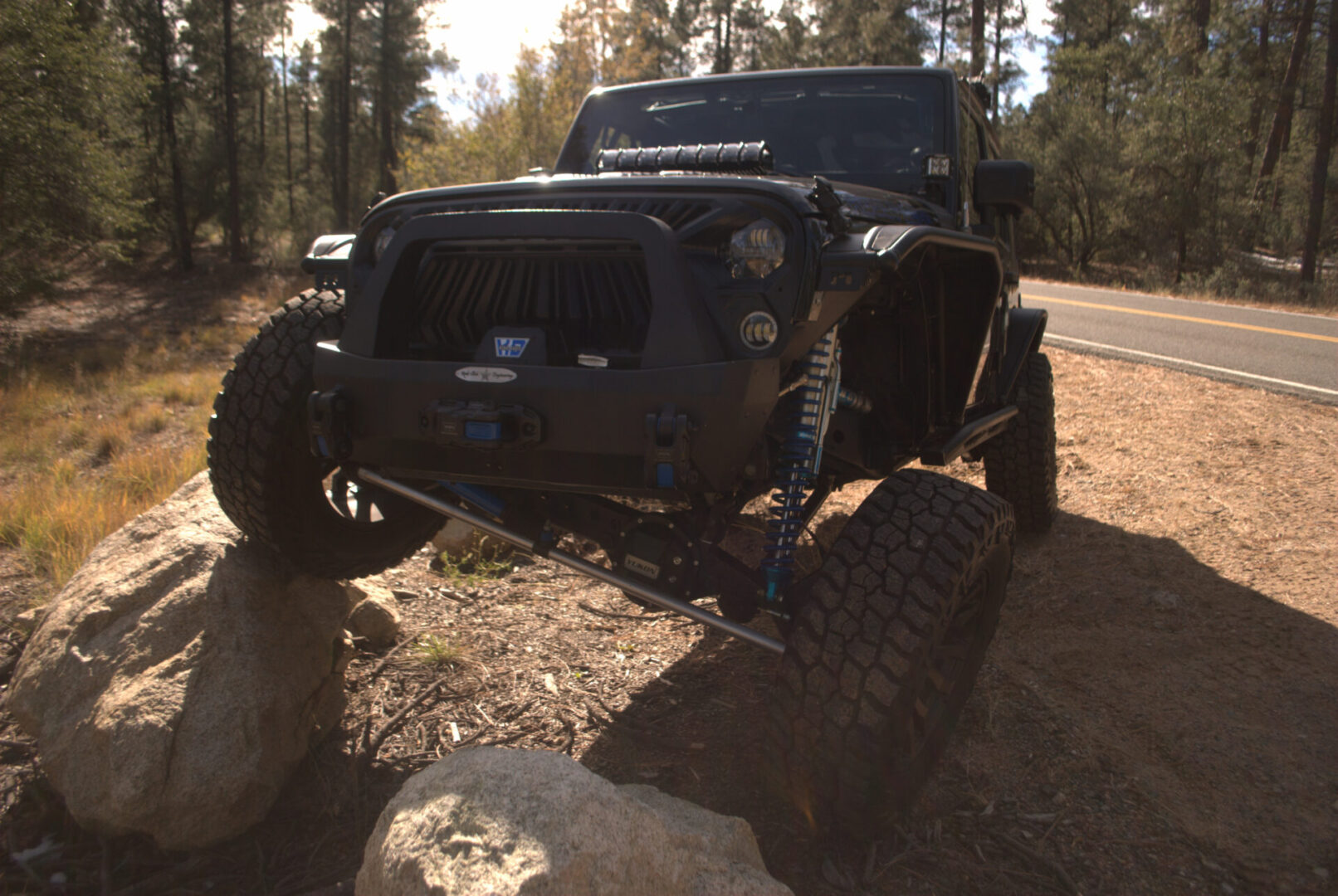 A jeep is parked on a rock in the woods.