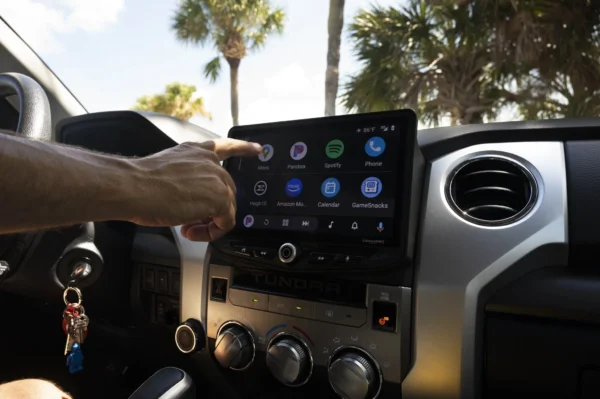 A man in a Toyota Tundra (2014-2021) HEIGH10 10" Touch Screen Radio Plug-and-Play Kit is using the car's gps system.